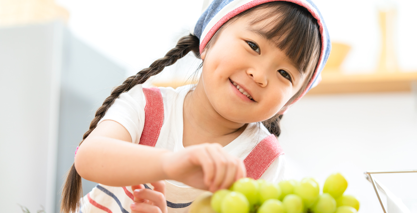 ブドウを食べて晴ればれ笑顔の女の子の写真