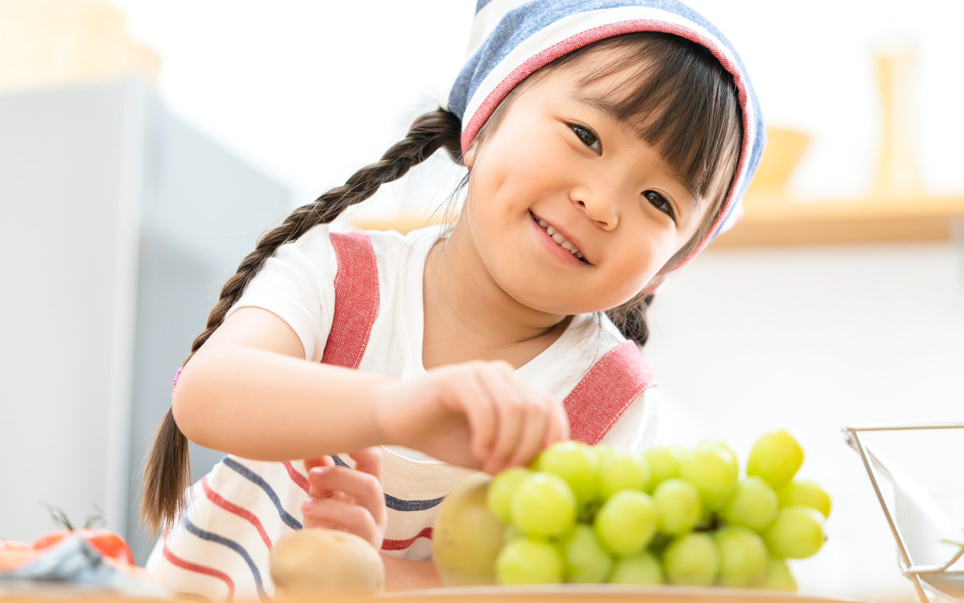 ブドウを食べて晴ればれ笑顔の女の子の写真