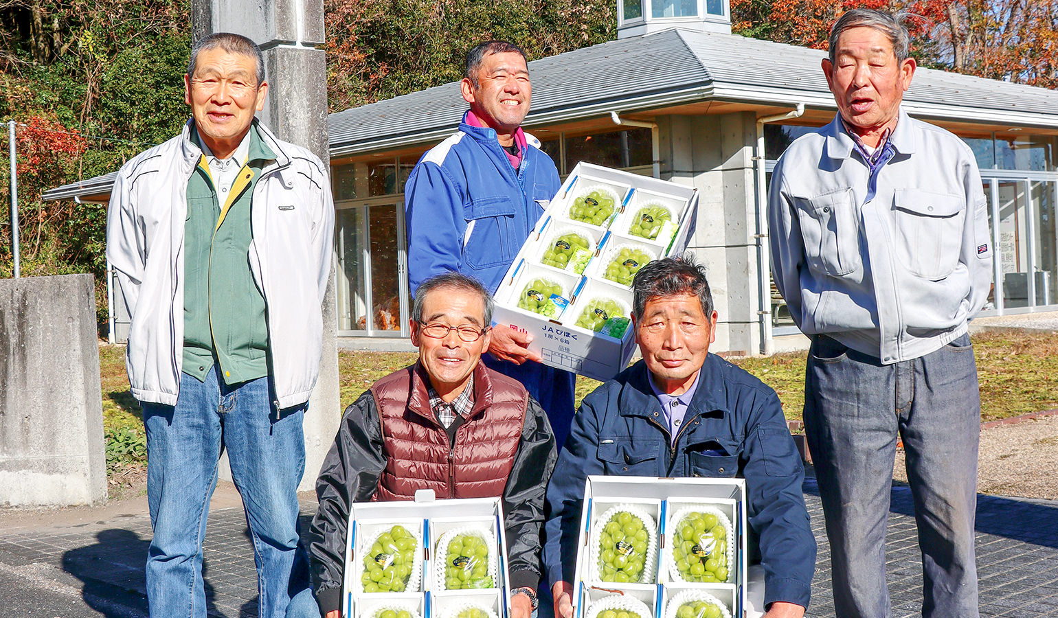 箱詰めした氷温ブドウ持つ生産者たちの写真