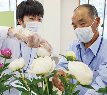 草丈・花姿などを審査する荒木一郎部会長（右）と関係者の写真