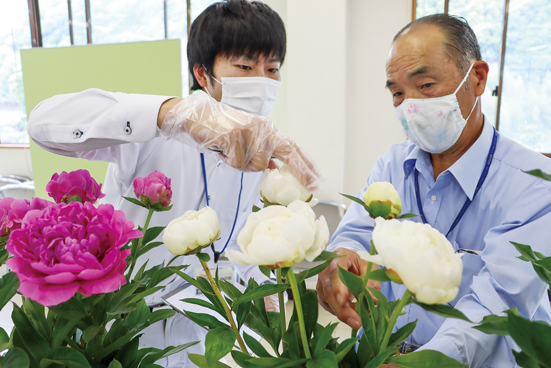 草丈・花姿などを審査する荒木一郎部会長（右）と関係者の写真