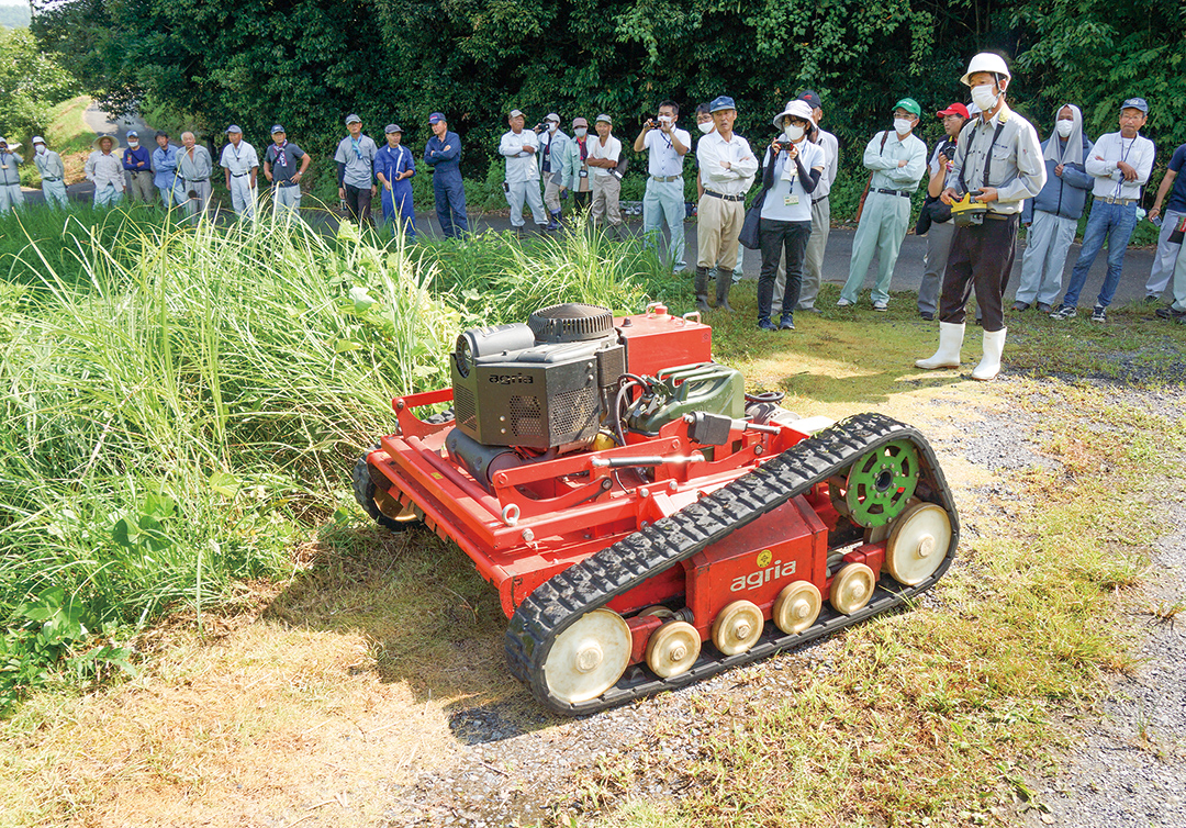 リモコン式自走草刈り機の実演に見入る参加者の写真