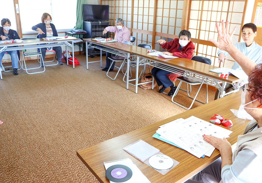 部員(右)から手話を学ぶ参加者の写真