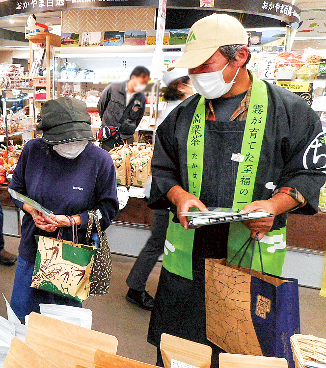 来場者にびほく産茶をPRする浦田さん（右）の写真