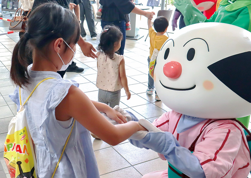 イベント後の握手会でアンパンマンたちとふれあう幼児の写真