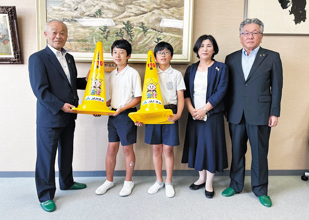 内藤組合長(左)からコーンを受け取る児童らの写真