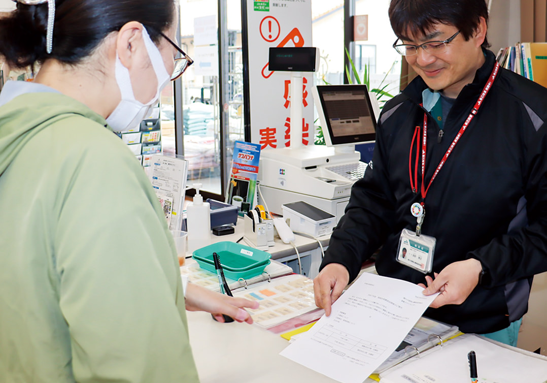 来店者に次回の講習会のお知らせをする職員（右）の写真